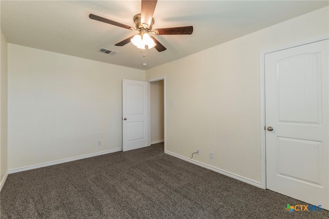 spare room featuring ceiling fan and dark carpet