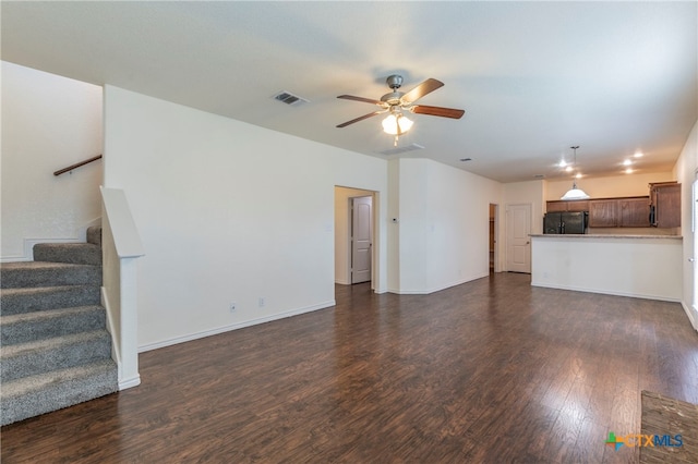 unfurnished living room featuring dark wood-type flooring and ceiling fan