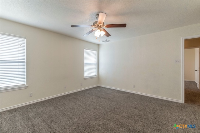 spare room with ceiling fan, a textured ceiling, and dark carpet