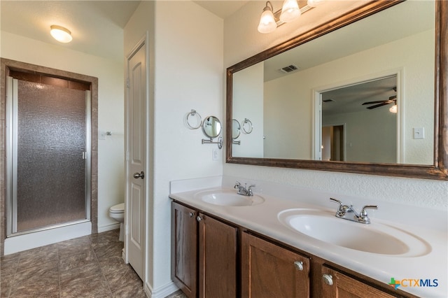 bathroom featuring toilet, vanity, ceiling fan, and a shower with shower door