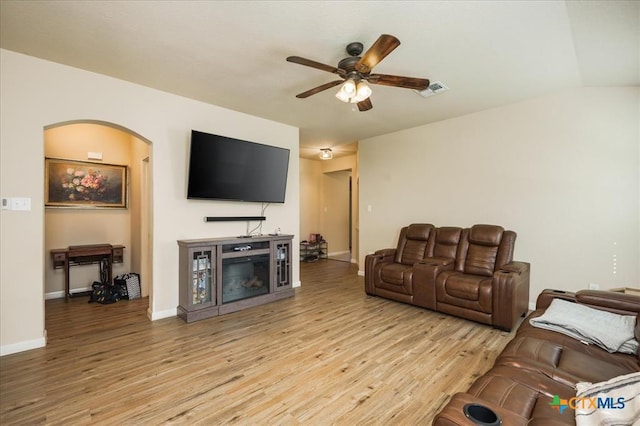 living room with light hardwood / wood-style floors, vaulted ceiling, and ceiling fan