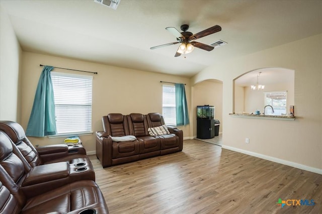 living room featuring sink, plenty of natural light, ceiling fan with notable chandelier, and light wood-type flooring