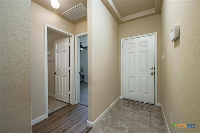 doorway with light tile patterned floors and ceiling fan