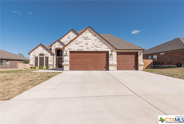 french country home featuring a front lawn and a garage