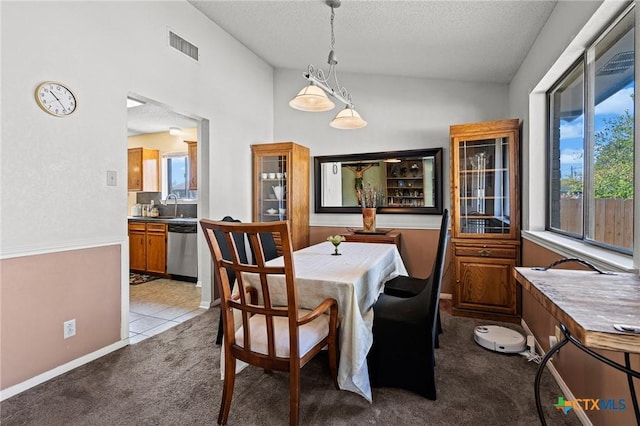 carpeted dining space with sink, vaulted ceiling, and a textured ceiling