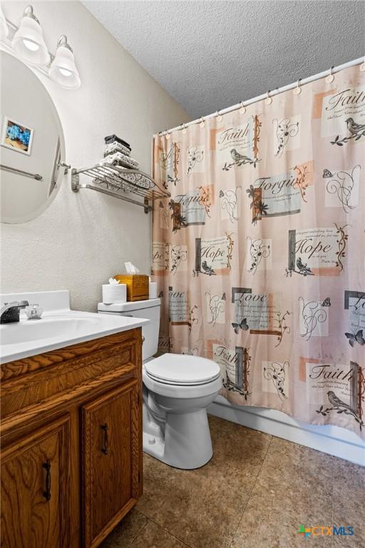 full bathroom with vanity, toilet, a textured ceiling, and shower / bath combo with shower curtain