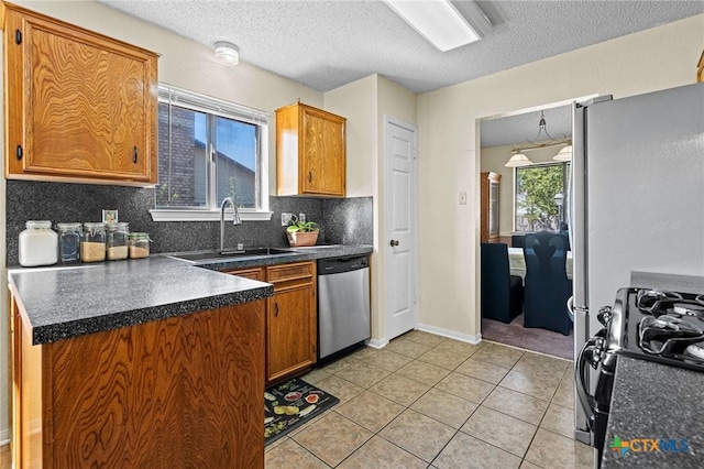 kitchen with sink, light tile patterned floors, backsplash, gas range oven, and stainless steel dishwasher