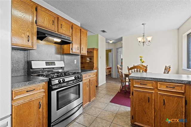 kitchen with light tile patterned flooring, stainless steel gas range oven, tasteful backsplash, a notable chandelier, and pendant lighting