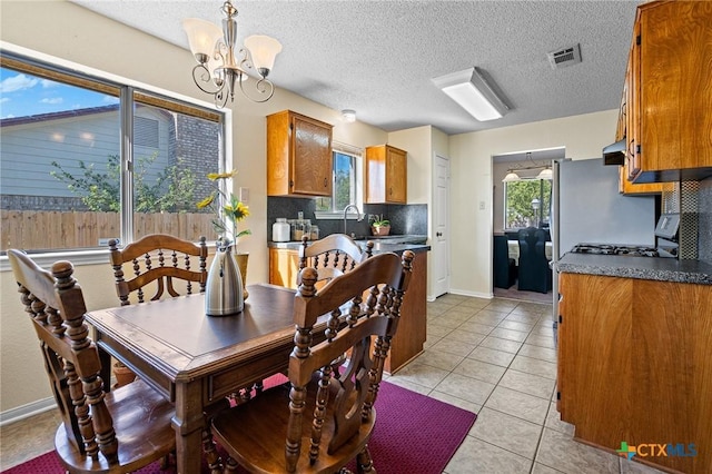 dining space with light tile patterned flooring, a textured ceiling, and an inviting chandelier