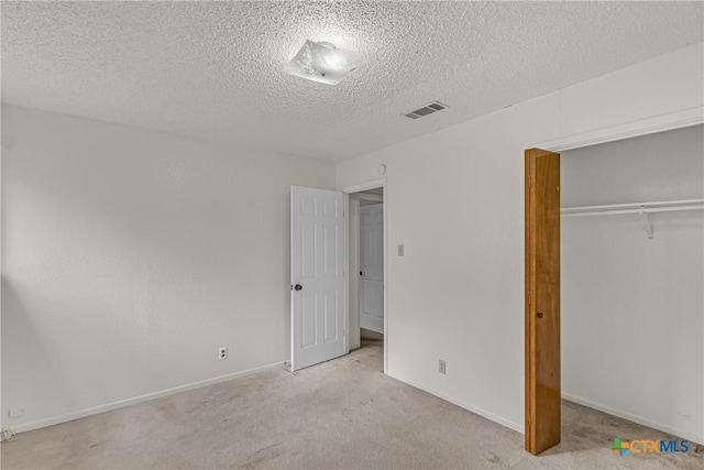 unfurnished bedroom with light colored carpet, a textured ceiling, and a closet