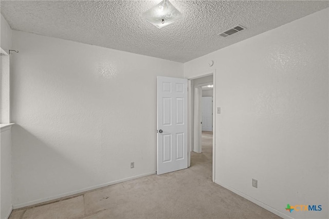 empty room featuring light carpet and a textured ceiling