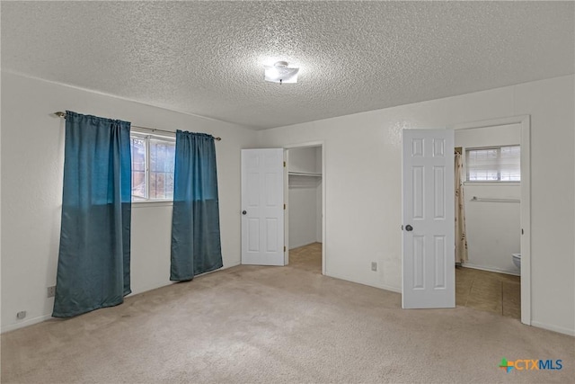 unfurnished bedroom with carpet floors, a textured ceiling, and multiple windows