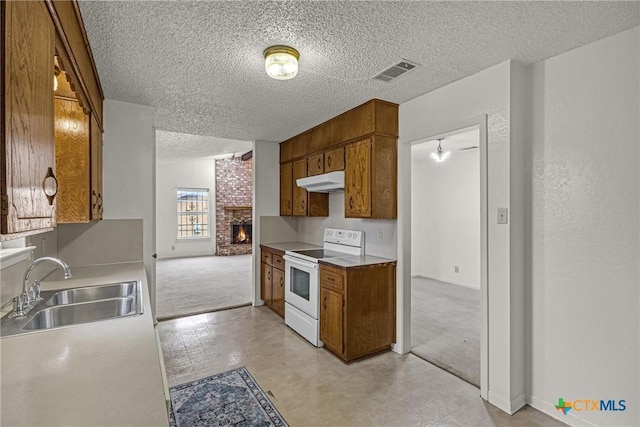 kitchen with a textured ceiling, sink, a brick fireplace, and electric stove