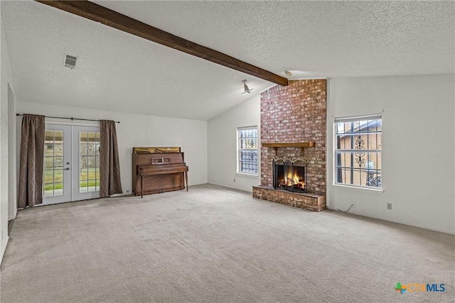 unfurnished living room with carpet, lofted ceiling with beams, a wealth of natural light, and a brick fireplace