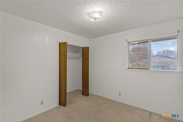 unfurnished bedroom featuring light colored carpet, a textured ceiling, and a closet