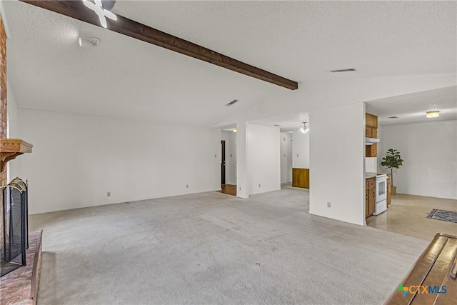 unfurnished living room with vaulted ceiling with beams, light carpet, a fireplace, and a textured ceiling