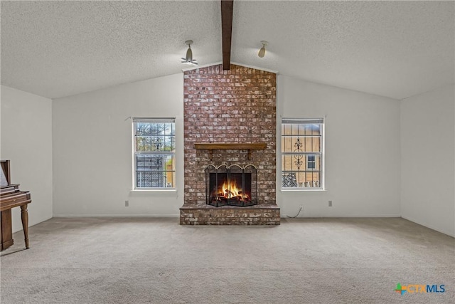 unfurnished living room with carpet, vaulted ceiling with beams, ceiling fan, a fireplace, and a textured ceiling