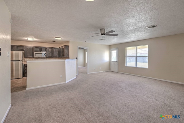 unfurnished living room featuring light carpet, a textured ceiling, and ceiling fan