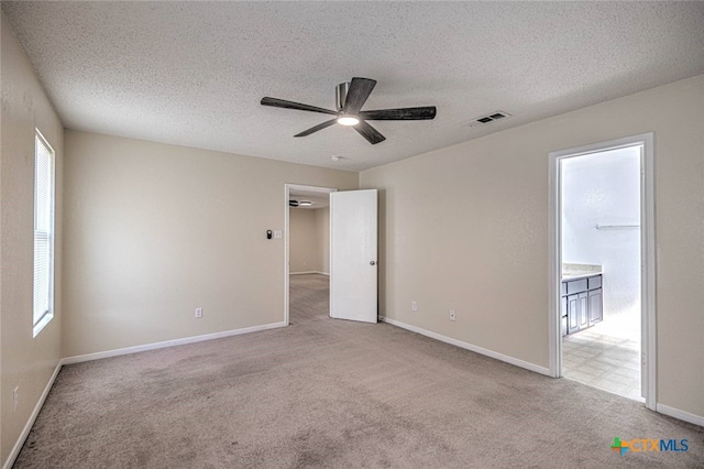 carpeted spare room featuring plenty of natural light, a textured ceiling, and ceiling fan