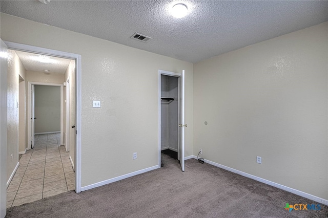 unfurnished bedroom with a textured ceiling, light carpet, and a closet