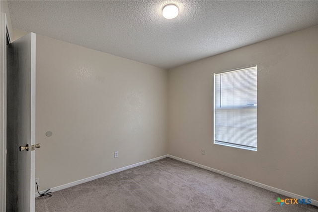 empty room with a textured ceiling and light carpet