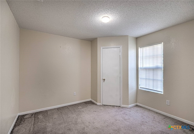 empty room with light colored carpet and a textured ceiling