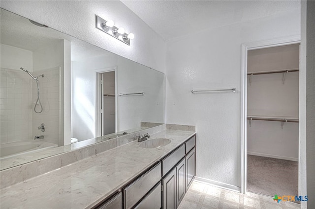 full bathroom featuring tiled shower / bath, vanity, a textured ceiling, and toilet