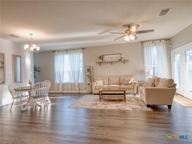 living room with dark wood-type flooring and ceiling fan with notable chandelier