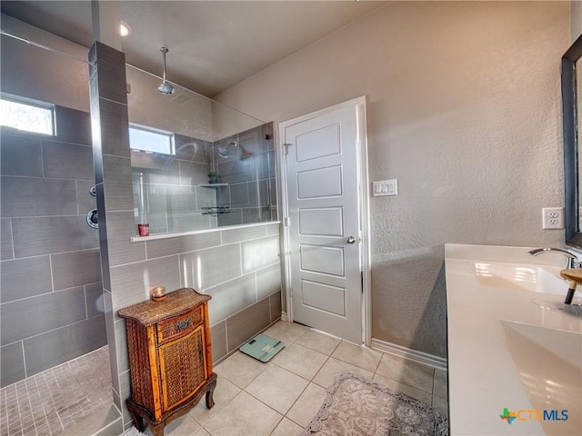 bathroom featuring a tile shower, vanity, and tile patterned floors