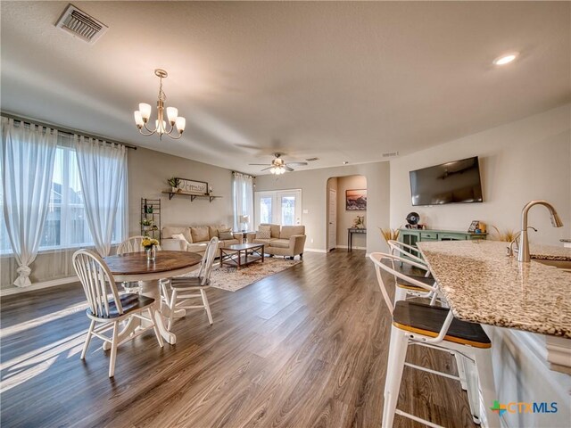 dining area featuring dark wood-type flooring, ceiling fan with notable chandelier, sink, and a wealth of natural light