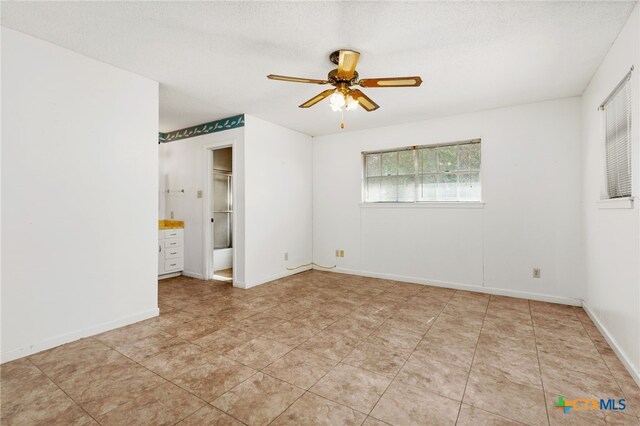 unfurnished bedroom with ceiling fan, a walk in closet, a textured ceiling, and connected bathroom