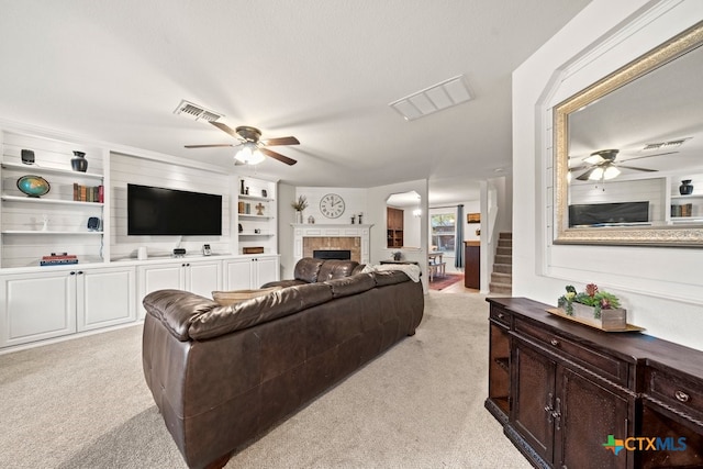 living room with ceiling fan, light carpet, and a tile fireplace