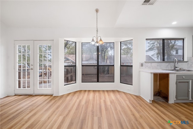 unfurnished dining area with light wood-type flooring, a healthy amount of sunlight, and sink