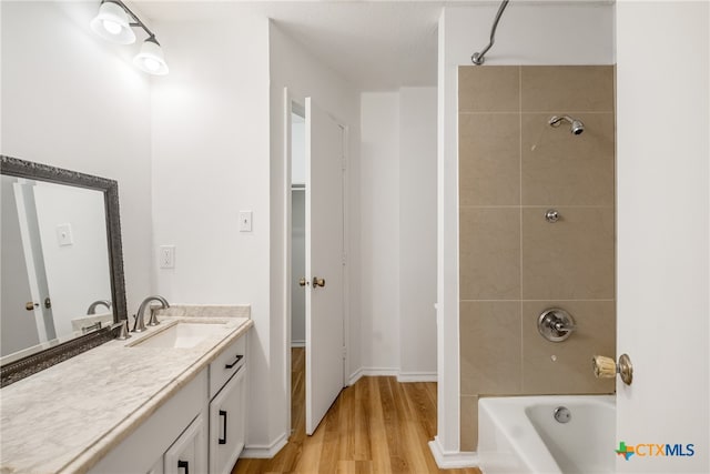 bathroom featuring hardwood / wood-style floors, vanity, and tiled shower / bath combo