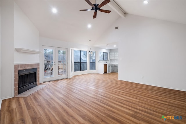 unfurnished living room featuring french doors, beamed ceiling, high vaulted ceiling, light hardwood / wood-style floors, and ceiling fan with notable chandelier