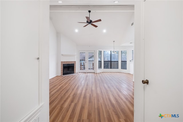 unfurnished living room with french doors, a brick fireplace, ceiling fan, wood-type flooring, and high vaulted ceiling