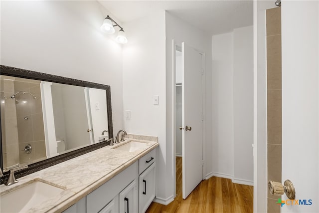 bathroom with vanity, a tile shower, and wood-type flooring