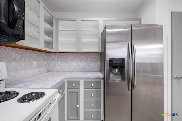 kitchen with white cabinets, stainless steel fridge, tasteful backsplash, and electric stove