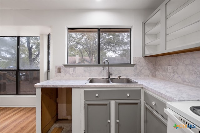 kitchen featuring decorative backsplash, gray cabinets, light hardwood / wood-style floors, and sink