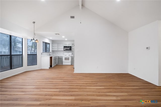 unfurnished living room featuring beam ceiling, high vaulted ceiling, a notable chandelier, and light wood-type flooring