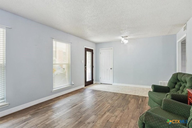 foyer entrance with wood finished floors, a textured ceiling, and baseboards