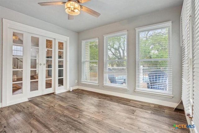 unfurnished sunroom featuring french doors, baseboards, wood finished floors, and a deck