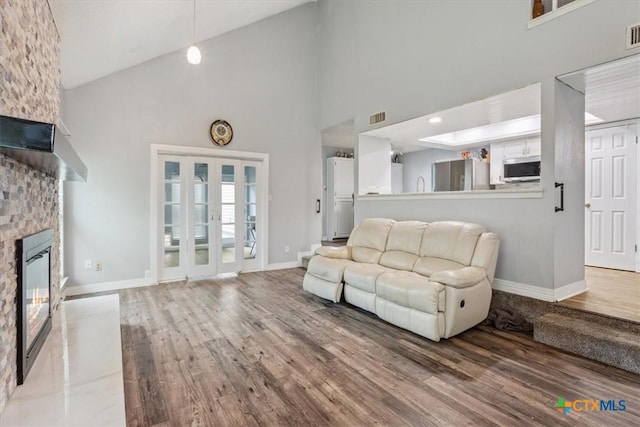 living room with high vaulted ceiling, wood finished floors, baseboards, and a fireplace