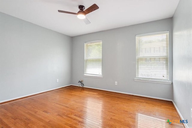 empty room featuring ceiling fan, hardwood / wood-style floors, and baseboards