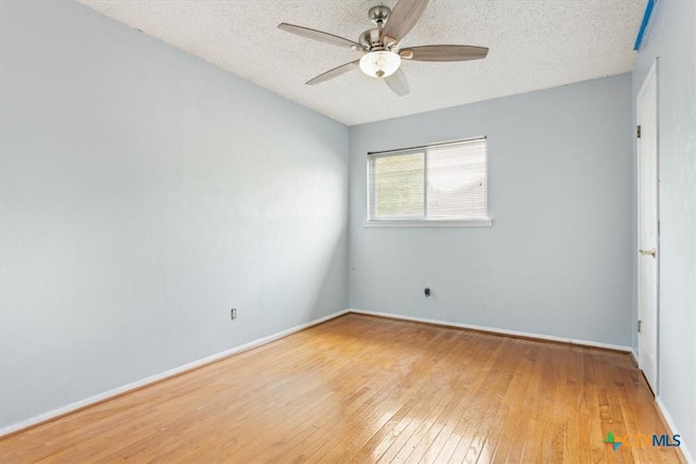 spare room with hardwood / wood-style floors, a textured ceiling, a ceiling fan, and baseboards