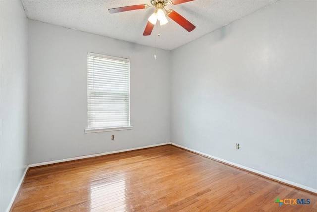 unfurnished room featuring wood finished floors, ceiling fan, baseboards, and a textured ceiling
