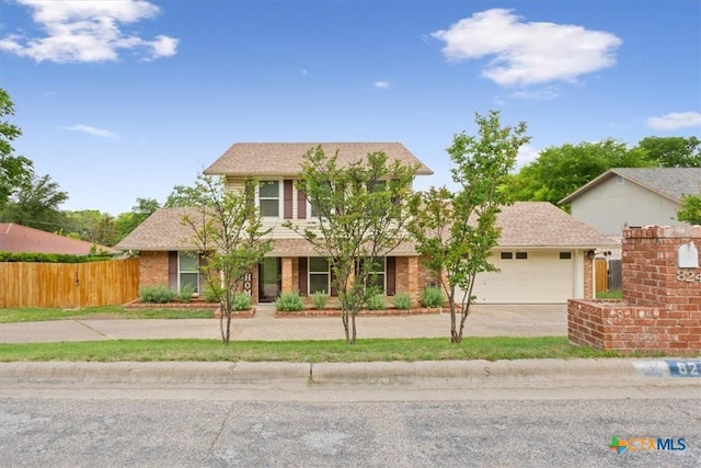 view of front of home with concrete driveway, fence, and an attached garage