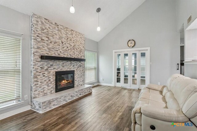 living area featuring high vaulted ceiling, wood finished floors, baseboards, and a fireplace