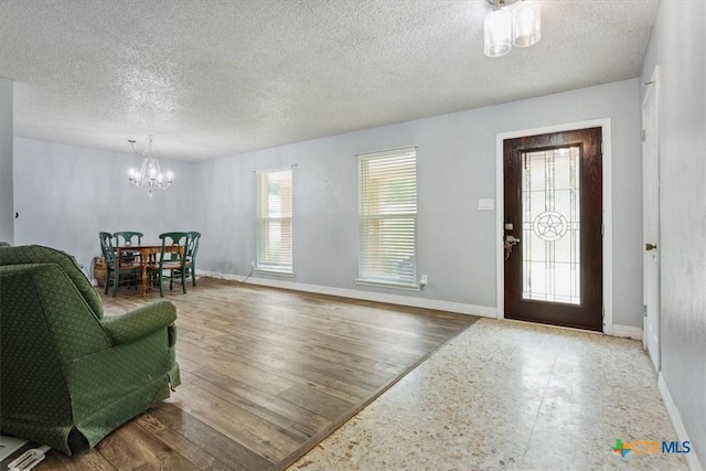 foyer featuring a chandelier, a textured ceiling, and baseboards