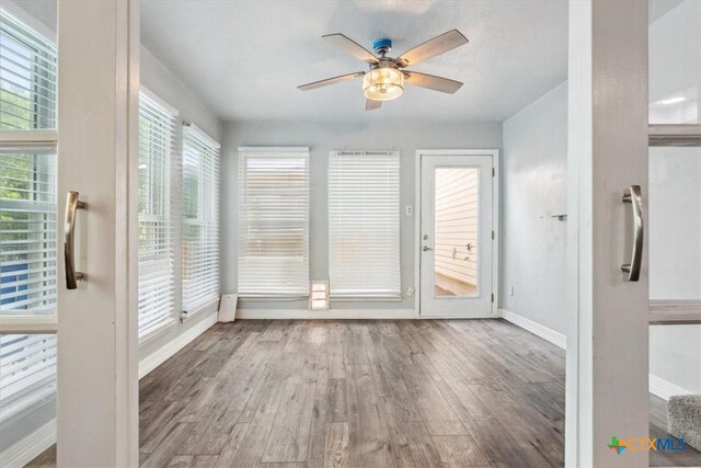 unfurnished sunroom featuring baseboards and wood finished floors